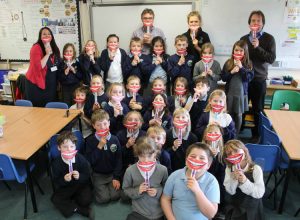 Class of children holding up smiling mouths